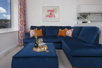 a living room with a blue couch and orange pillows at Pink Sands, Carrack Widden, St Ives in St Ives
