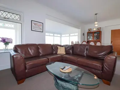 a living room with a brown leather couch and a glass table at 1 Atlantic View in Newquay