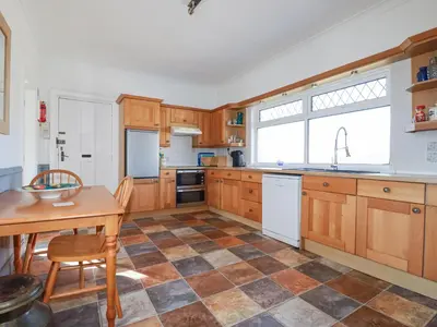 a kitchen with wooden cabinets and a table and a sink at 1 Atlantic View in Newquay