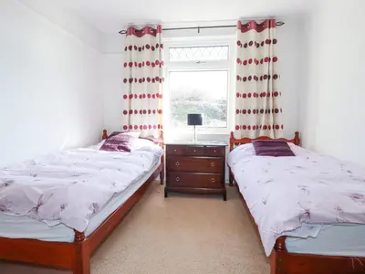 two twin beds in a bedroom with a window at 1 Atlantic View in Newquay