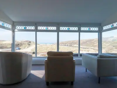a living room with two chairs and large windows at 1 Atlantic View in Newquay