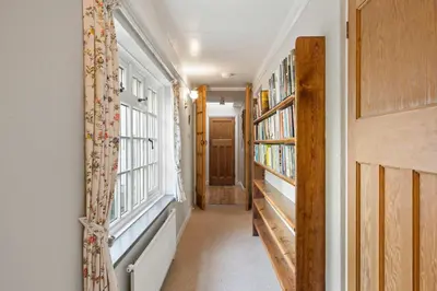 a hallway with two windows and bookshelves and a door at Homely Cottage & Garden nr Praa Sands & Marazion in Saint Hilary