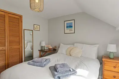 a bedroom with a white bed with towels on it at Homely Cottage & Garden nr Praa Sands & Marazion in Saint Hilary