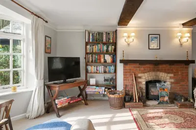 a living room with a fireplace and a television at Homely Cottage & Garden nr Praa Sands & Marazion in Saint Hilary