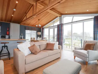 a living room with a couch and a kitchen at 6 Meadow Retreat in Liskeard