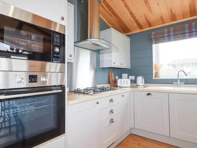 a kitchen with white cabinets and a stove top oven at 6 Meadow Retreat in Liskeard