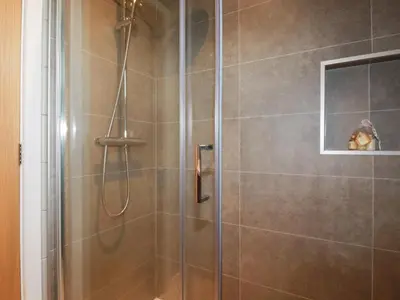 a shower with a glass door with a dog in a window at 6 Meadow Retreat in Liskeard