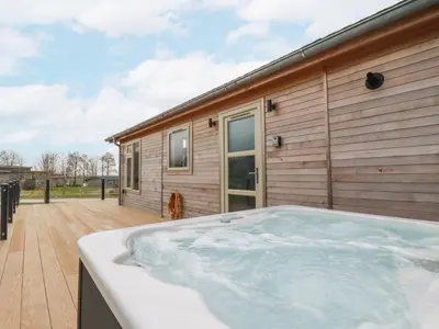 a hot tub on a deck next to a house at 6 Meadow Retreat in Liskeard