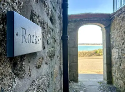 a sign on the side of a stone wall with a door at 'Rocks' Sea Views with free parking in St Ives in St Ives