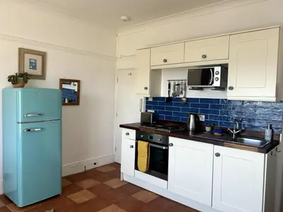a kitchen with a blue refrigerator and white cabinets at 'Rocks' Sea Views with free parking in St Ives in St Ives