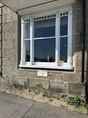 a window on a brick building with a sign in it at 'Rocks' Sea Views with free parking in St Ives in St Ives