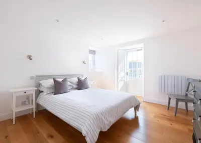 a white bedroom with a large white bed with pillows at First-Floor Georgian Apartment with Terrace and Sea Views in Boscastle in Boscastle