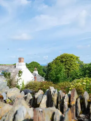 a view of a house from behind a stone fence at First-Floor Georgian Apartment with Terrace and Sea Views in Boscastle in Boscastle