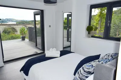 a bedroom with a bed and a large window at Riverview Modern 2 Bed- Parking & Tesla charger in Penryn
