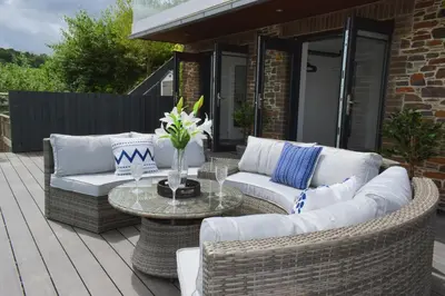 a patio with wicker furniture and a glass table at Riverview Modern 2 Bed- Parking & Tesla charger in Penryn