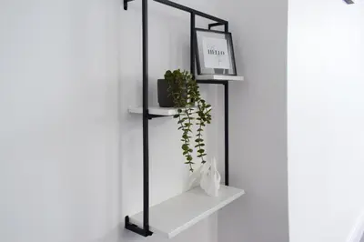 a black shelf with a plant on a wall at Riverview Modern 2 Bed- Parking & Tesla charger in Penryn