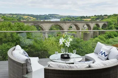 a patio with a table and chairs on a balcony at Riverview Modern 2 Bed- Parking & Tesla charger in Penryn