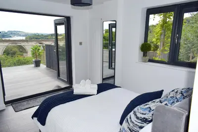 a bedroom with a bed and a large window at Riverview Modern 2 Bed- Parking & Tesla charger in Penryn