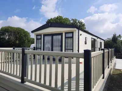 a tiny house with a fence at Luxury 6 berth caravan full decking in Saint Columb Minor