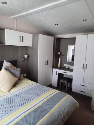 a bedroom with a bed and a desk and white cabinets at Luxury 6 berth caravan full decking in Saint Columb Minor