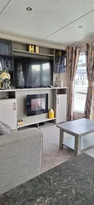 a living room with a tv and a couch and a table at Luxury 6 berth caravan full decking in Saint Columb Minor
