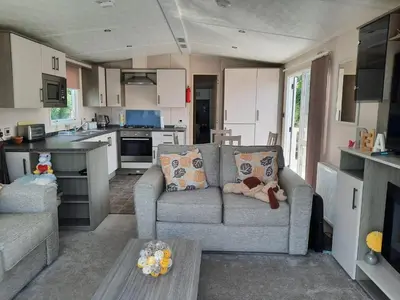 a living room with a couch and a kitchen at Luxury 6 berth caravan full decking in Saint Columb Minor