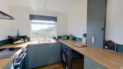 a kitchen with blue cabinets and a sink and a window at G17 St Meva, Riviere Towans in Hayle