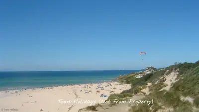 a group of people on a beach flying a kite at G17 St Meva, Riviere Towans in Hayle