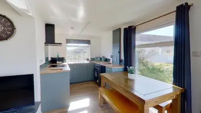 a kitchen with a table and a clock on the wall at G17 St Meva, Riviere Towans in Hayle