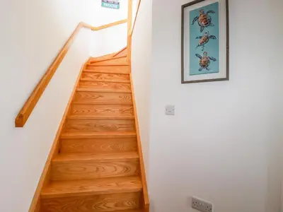 a staircase in a house with wooden floors at Jacana in Perranporth