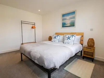 a bedroom with a large bed with blue pillows at Jacana in Perranporth