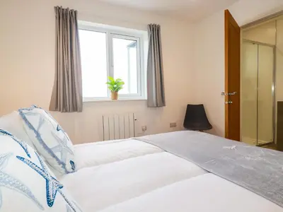 a bedroom with a large bed with a window at Jacana in Perranporth