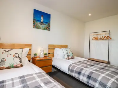 a bedroom with two beds and a clock on the wall at Jacana in Perranporth