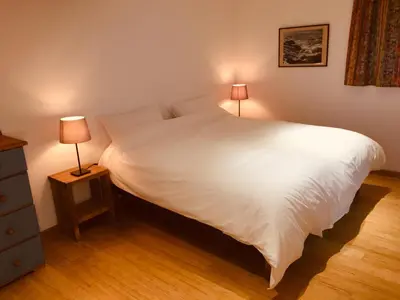 a bedroom with a large white bed with two lamps at Seaview Studio in Forrabury