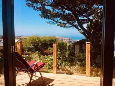 a chair on a porch with a view of the ocean at Seaview Studio in Forrabury