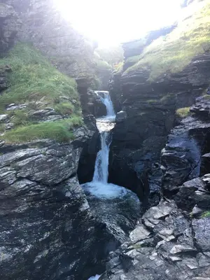 a waterfall on the side of a rocky mountain at Seaview Studio in Forrabury
