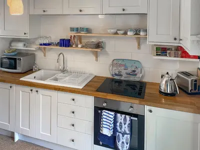 a kitchen with white cabinets and a sink at Issys Cottage in Helston