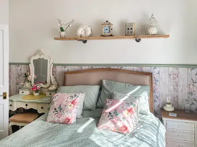 a bedroom with a bed with two pillows and a mirror at Issys Cottage in Helston