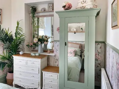 a bedroom with a bed and a dresser and a mirror at Issys Cottage in Helston