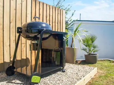 a grill sitting in a yard next to a fence at Chlobo Cottage in Porth