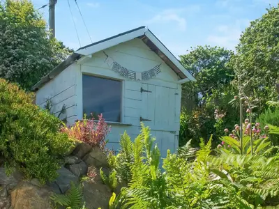 a shed in a garden with plants at Chlobo Cottage in Porth