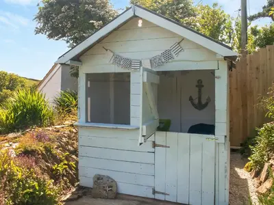 a white shed with an open door with an anchor on it at Chlobo Cottage in Porth
