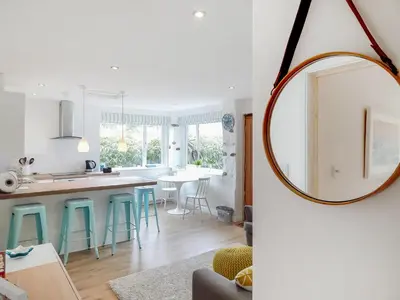 a kitchen and living room with a round mirror at Chlobo Cottage in Porth