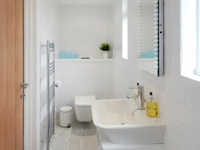 a white bathroom with a sink and a toilet at Chlobo Cottage in Porth