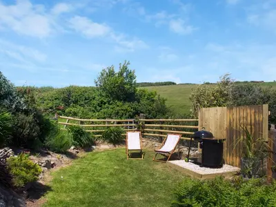 two chairs and a grill in a garden at Chlobo Cottage in Porth
