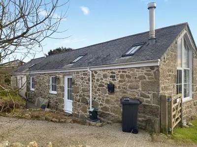 a stone cottage with a trash can in front of it at The Milking Parlour in St Ives