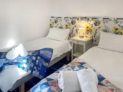a room with two beds and a table with a lamp at The Milking Parlour in St Ives