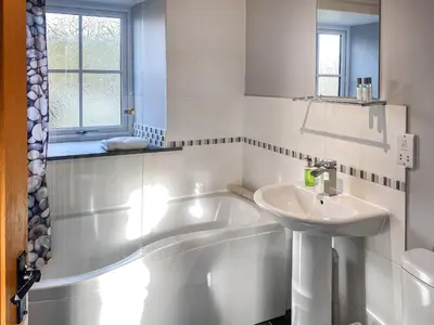 a white bathroom with a tub and a sink at The Milking Parlour in St Ives