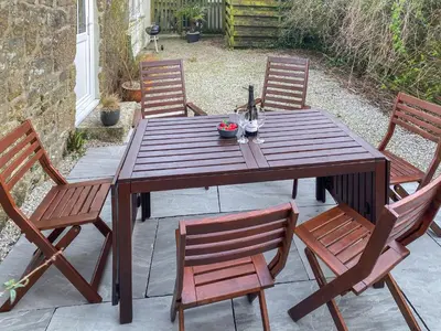 a wooden table with four chairs on a patio at The Milking Parlour in St Ives