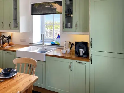 a kitchen with green cabinets and a sink and a window at The Milking Parlour in St Ives